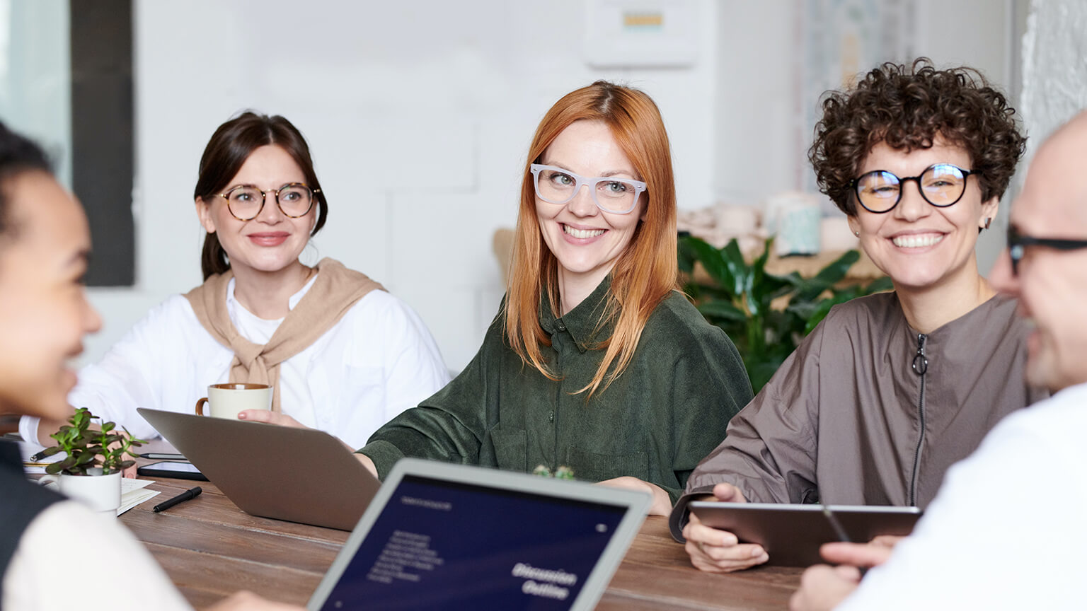 Eine Gruppe von Menschen sitzen im Büro und unterhalten sich.